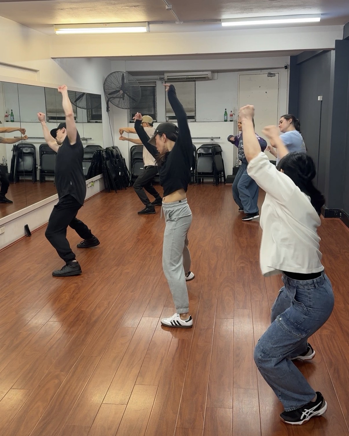 Dancers reaching an arm overhead together during a foundations drill in the studio